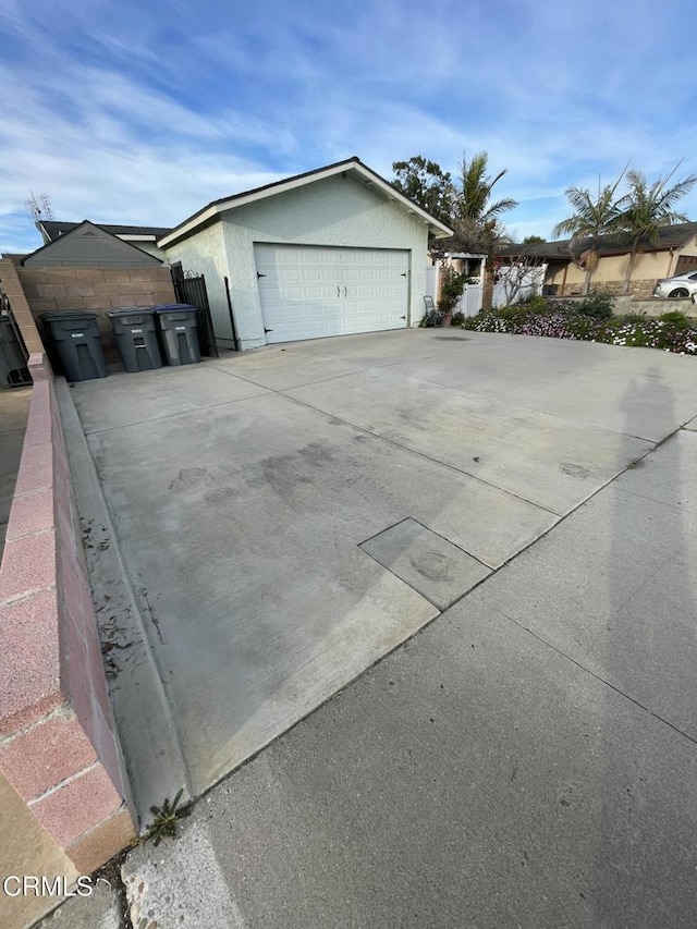 view of property exterior featuring a garage, fence, and stucco siding