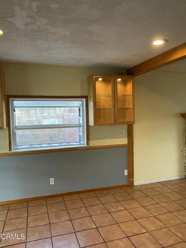 kitchen with recessed lighting, light tile patterned flooring, a textured ceiling, and baseboards