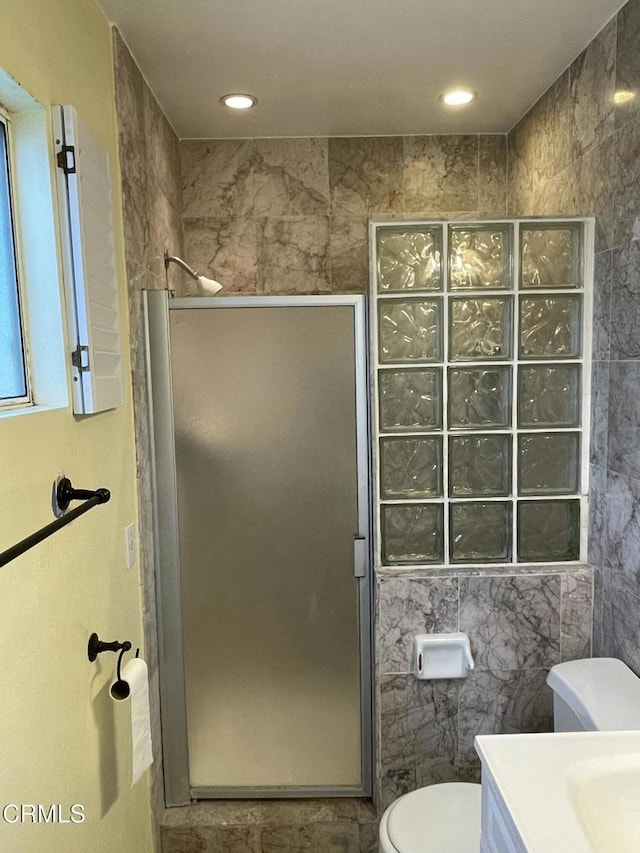 full bathroom with tile walls, recessed lighting, toilet, a stall shower, and vanity