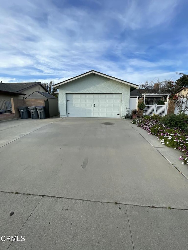 view of side of property with a detached garage, fence, and stucco siding