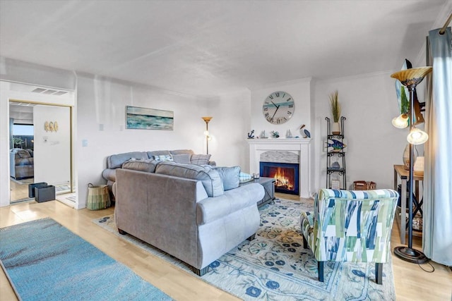 living area with a fireplace, visible vents, and light wood-type flooring