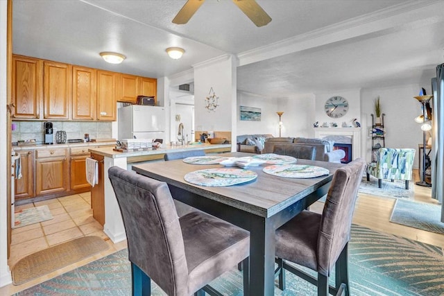 dining space featuring a ceiling fan, crown molding, and a fireplace