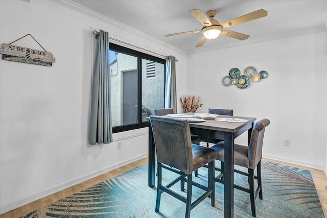 dining room featuring a ceiling fan, light wood-type flooring, baseboards, and ornamental molding