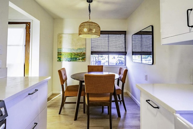 dining area with light wood-type flooring and baseboards