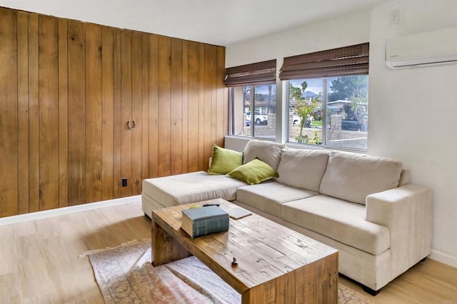 living room featuring light wood-type flooring, a wall unit AC, and wood walls