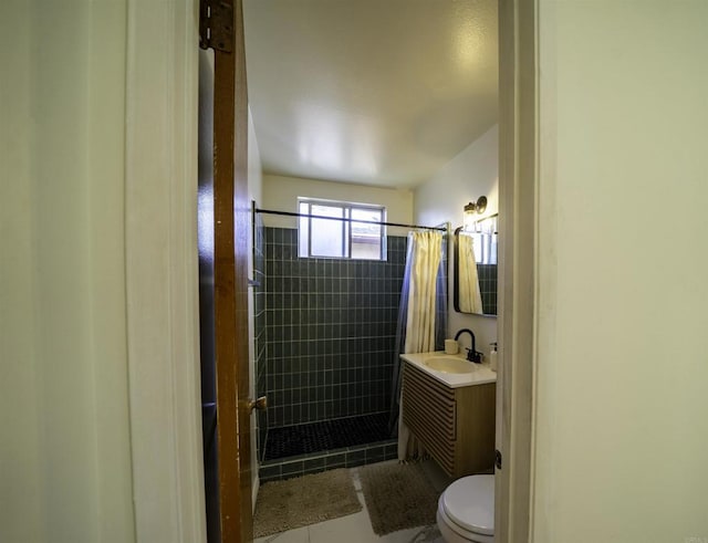 bathroom with tiled shower, vanity, toilet, and tile patterned floors