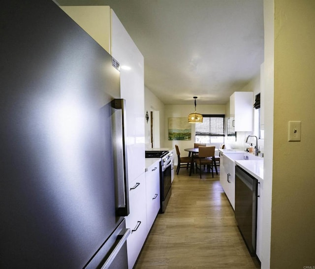 kitchen with appliances with stainless steel finishes, white cabinets, and a sink