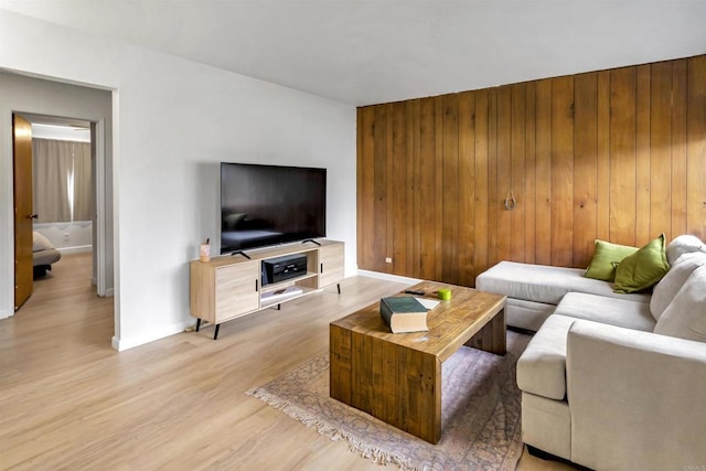 living area featuring wooden walls, light wood-style flooring, and baseboards