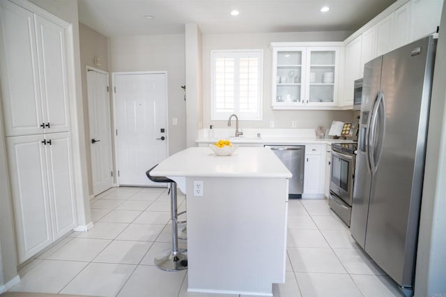 kitchen featuring light tile patterned floors, a breakfast bar area, white cabinetry, light countertops, and appliances with stainless steel finishes