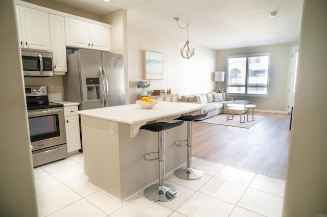 kitchen with light tile patterned floors, stainless steel appliances, light countertops, and open floor plan