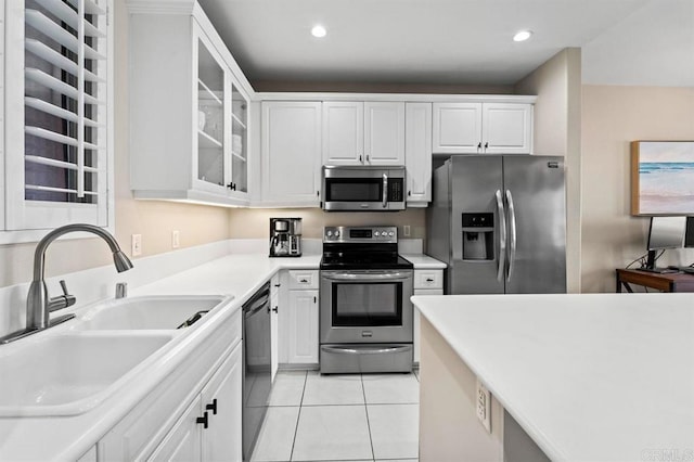 kitchen with light tile patterned floors, appliances with stainless steel finishes, glass insert cabinets, white cabinetry, and a sink