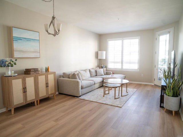 living room with a chandelier, light wood-type flooring, and baseboards