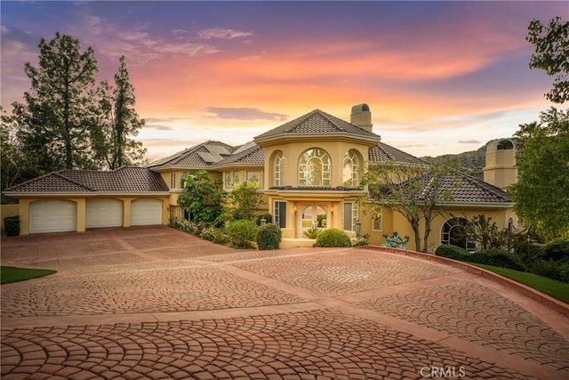 22537 N Summit Ridge Cir, Chatsworth, CA 91311 - mediterranean / spanish-style home with a chimney, stucco siding, curved driveway, an attached garage, and a tile roof