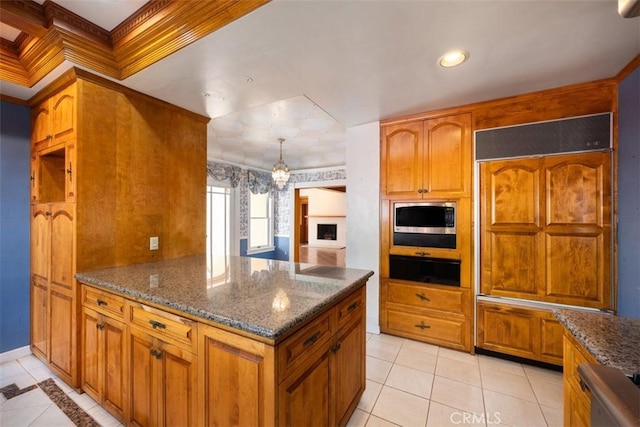 kitchen with brown cabinets, dark stone countertops, built in appliances, and crown molding