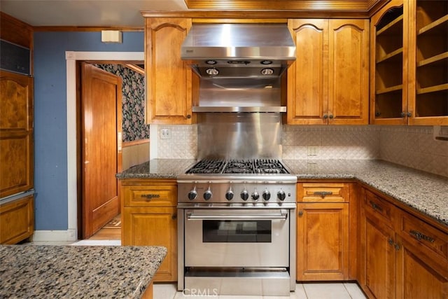 kitchen featuring light stone countertops, high end stainless steel range oven, tasteful backsplash, extractor fan, and brown cabinetry
