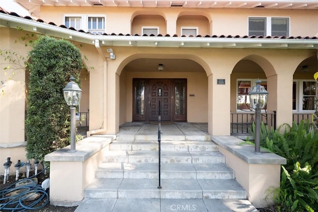 property entrance featuring stucco siding and covered porch