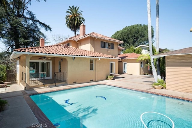rear view of property featuring a tile roof, a patio area, a chimney, stucco siding, and an outdoor pool