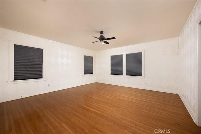 spare room featuring baseboards, wood finished floors, and ceiling fan