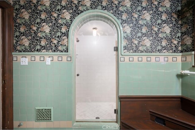 full bathroom with a shower stall, wallpapered walls, visible vents, and wainscoting