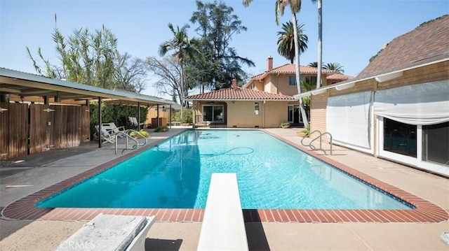 view of swimming pool with a diving board, a fenced in pool, and a patio