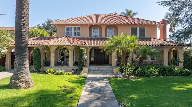 mediterranean / spanish-style home featuring stucco siding, a tile roof, a front lawn, and a porch
