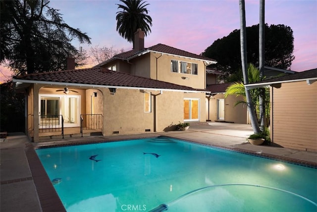 back of property with a tile roof, stucco siding, a patio, crawl space, and a chimney