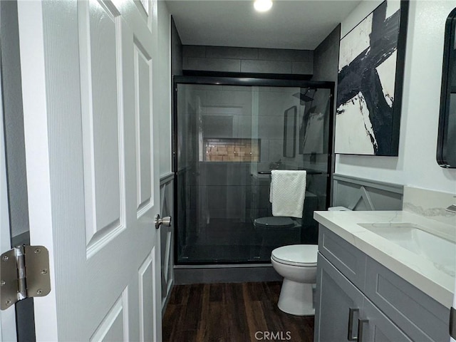 bathroom with vanity, a shower stall, toilet, and wood finished floors