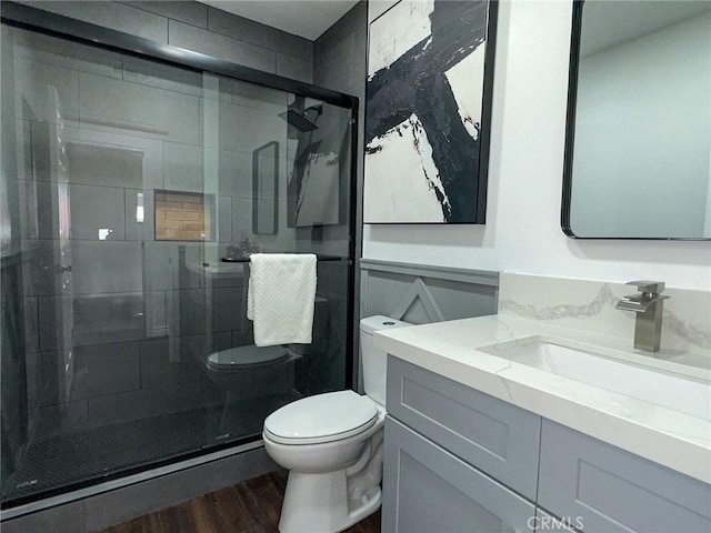 full bath featuring vanity, a stall shower, wood finished floors, and toilet