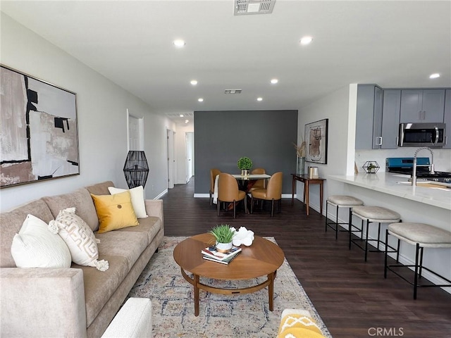 living area with recessed lighting, dark wood-style flooring, and visible vents