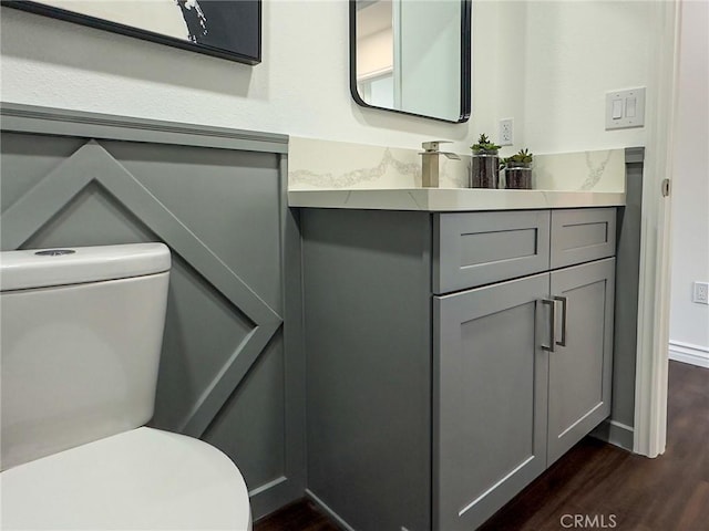 bathroom featuring baseboards, vanity, toilet, and wood finished floors