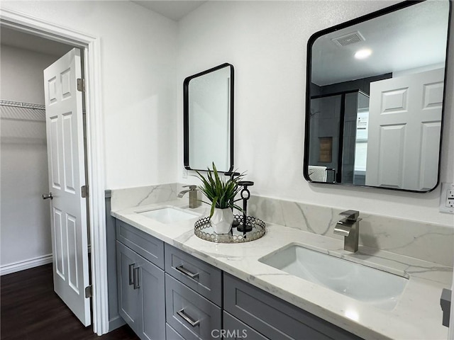 full bathroom featuring double vanity, wood finished floors, a sink, and visible vents