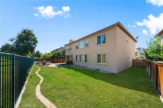 rear view of house featuring stucco siding, a fenced backyard, a patio, and a lawn