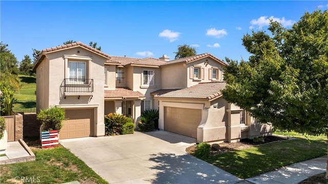 mediterranean / spanish-style home with a garage, a tiled roof, driveway, and stucco siding