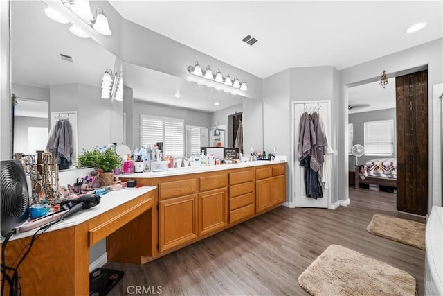 ensuite bathroom with double vanity, visible vents, connected bathroom, and wood finished floors