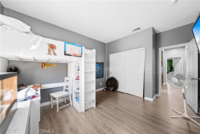 bedroom featuring light wood-type flooring, baseboards, visible vents, and a closet