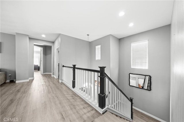 hallway with recessed lighting, baseboards, an upstairs landing, and wood finished floors