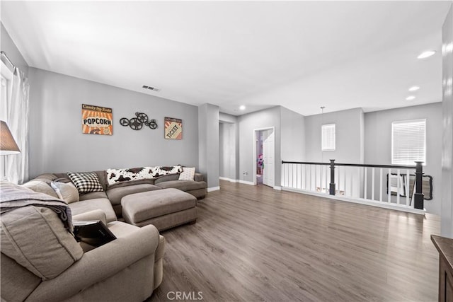 living room with baseboards, wood finished floors, visible vents, and recessed lighting