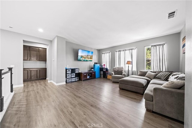 living room with light wood finished floors, visible vents, and baseboards