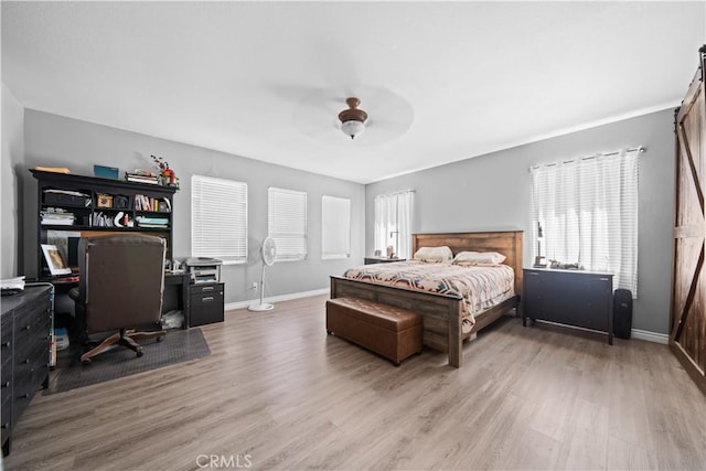 bedroom featuring a ceiling fan, multiple windows, baseboards, and wood finished floors