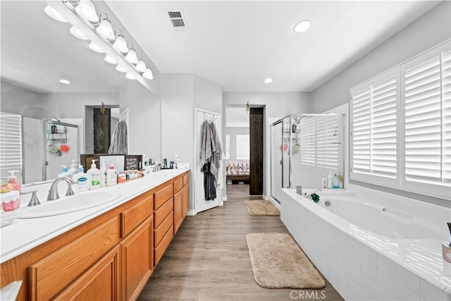 full bath with a sink, visible vents, a shower stall, a bath, and double vanity