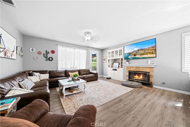 living area featuring a fireplace, wood finished floors, visible vents, and baseboards