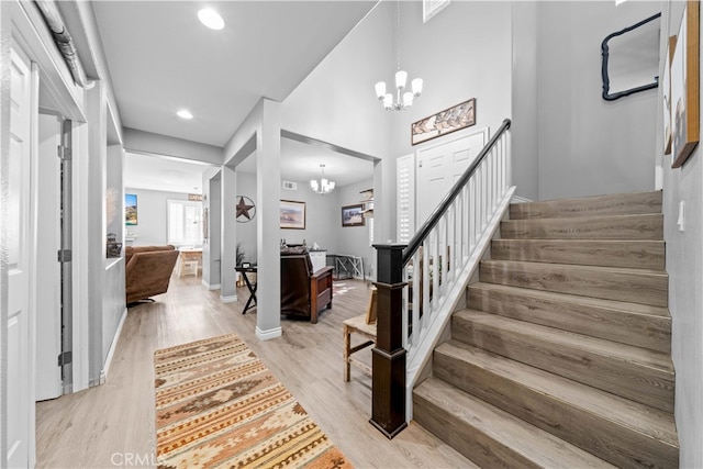 entrance foyer with recessed lighting, stairway, light wood-style floors, a chandelier, and baseboards