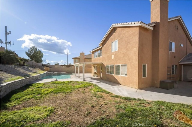 back of property with a chimney, a patio area, a fenced backyard, and stucco siding