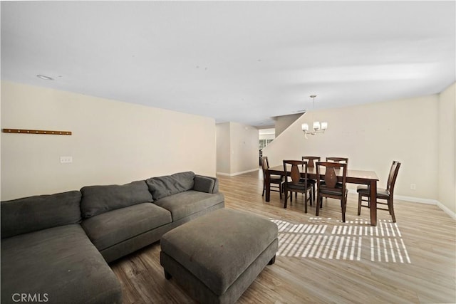 living room featuring a chandelier, light wood-style flooring, and baseboards