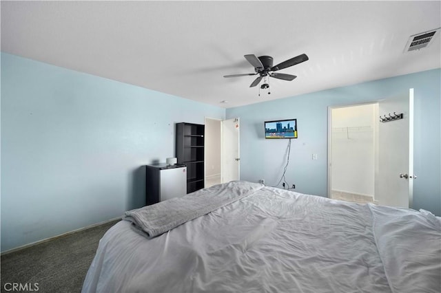 bedroom featuring carpet floors, ceiling fan, visible vents, and a walk in closet