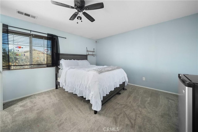 carpeted bedroom featuring freestanding refrigerator, visible vents, ceiling fan, and baseboards