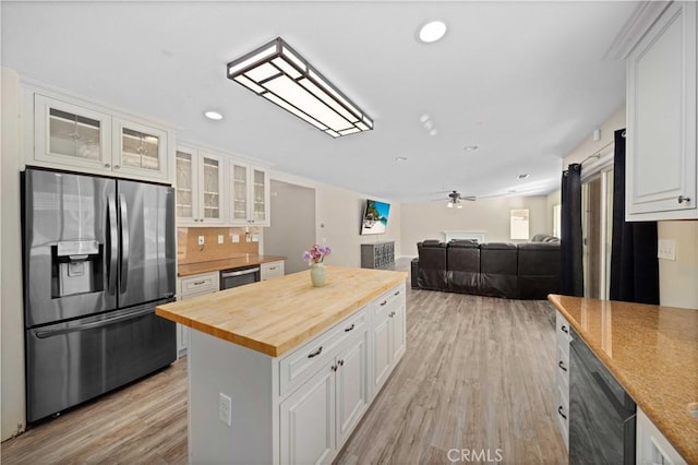 kitchen with light wood-style flooring, butcher block counters, white cabinetry, black dishwasher, and stainless steel fridge with ice dispenser