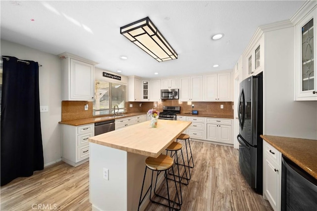 kitchen with wooden counters, appliances with stainless steel finishes, light wood-style floors, beverage cooler, and a kitchen bar