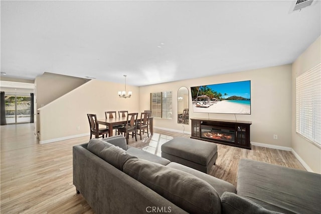 living area featuring light wood-style flooring, visible vents, baseboards, and a glass covered fireplace