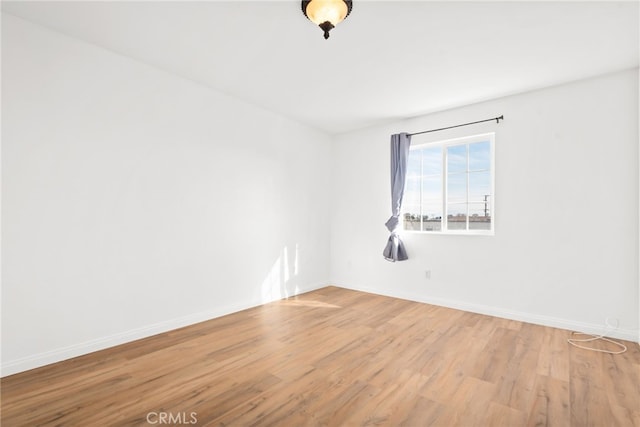 empty room with light wood finished floors and baseboards